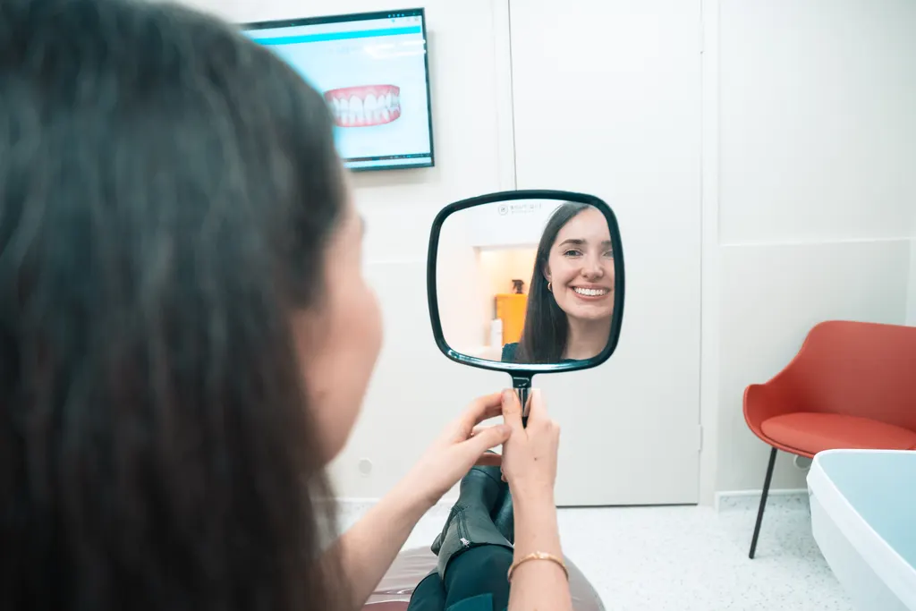 A patient smiling at her reflection in a hand mirror