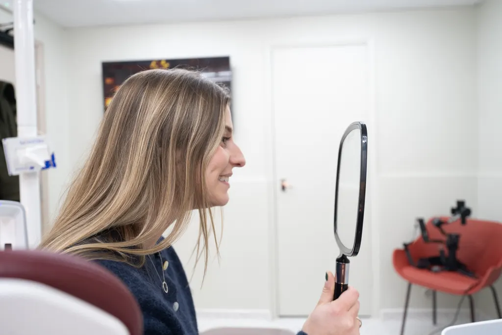 A patient checking her smile in a hand mirror