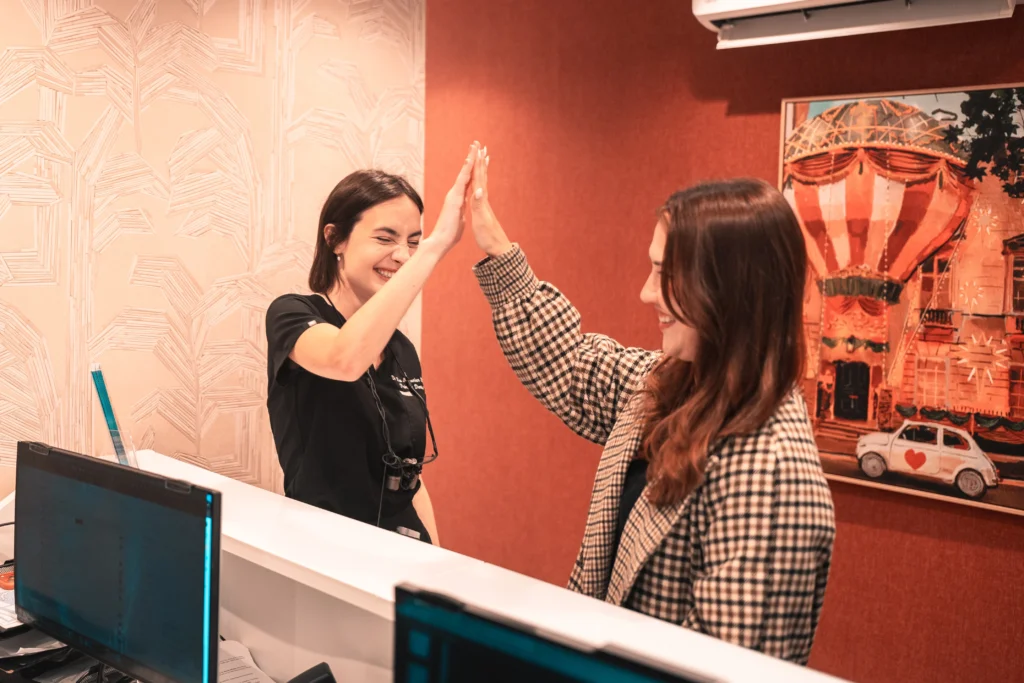 A Pearly Whites patient and dentist sharing a high five at reception