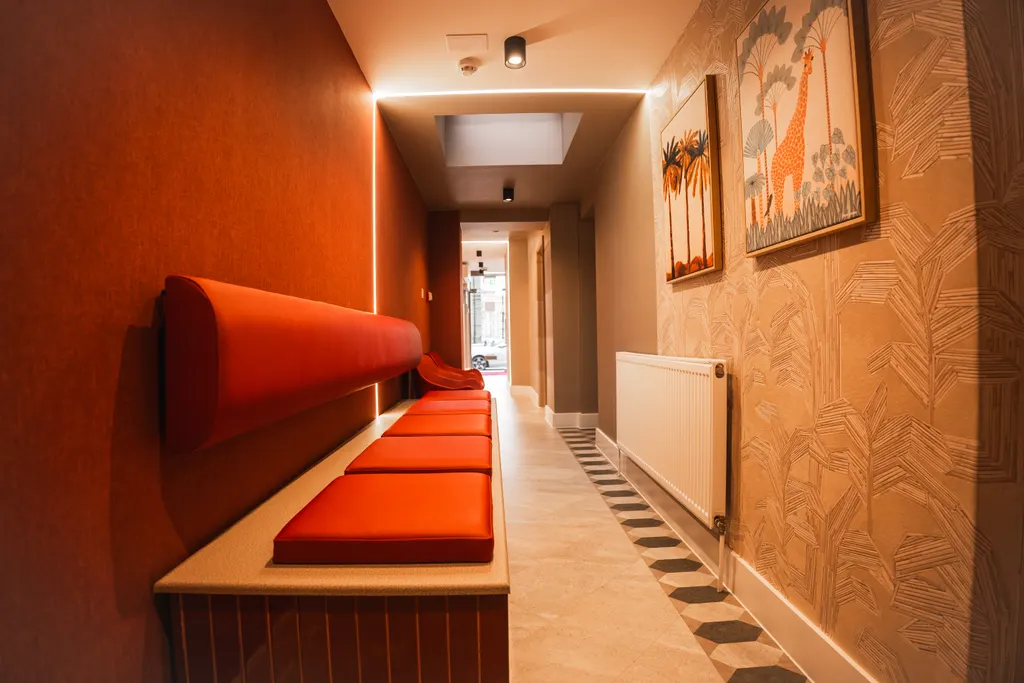 The corridor at Pearly Whites, with red banquette seating and art on the walls