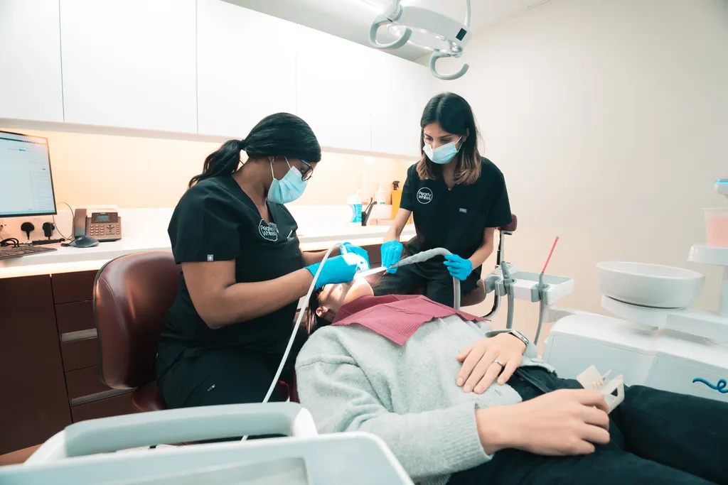 A Pearly Whites hygienist cleaning a patient’s teeth with AIRFLOW